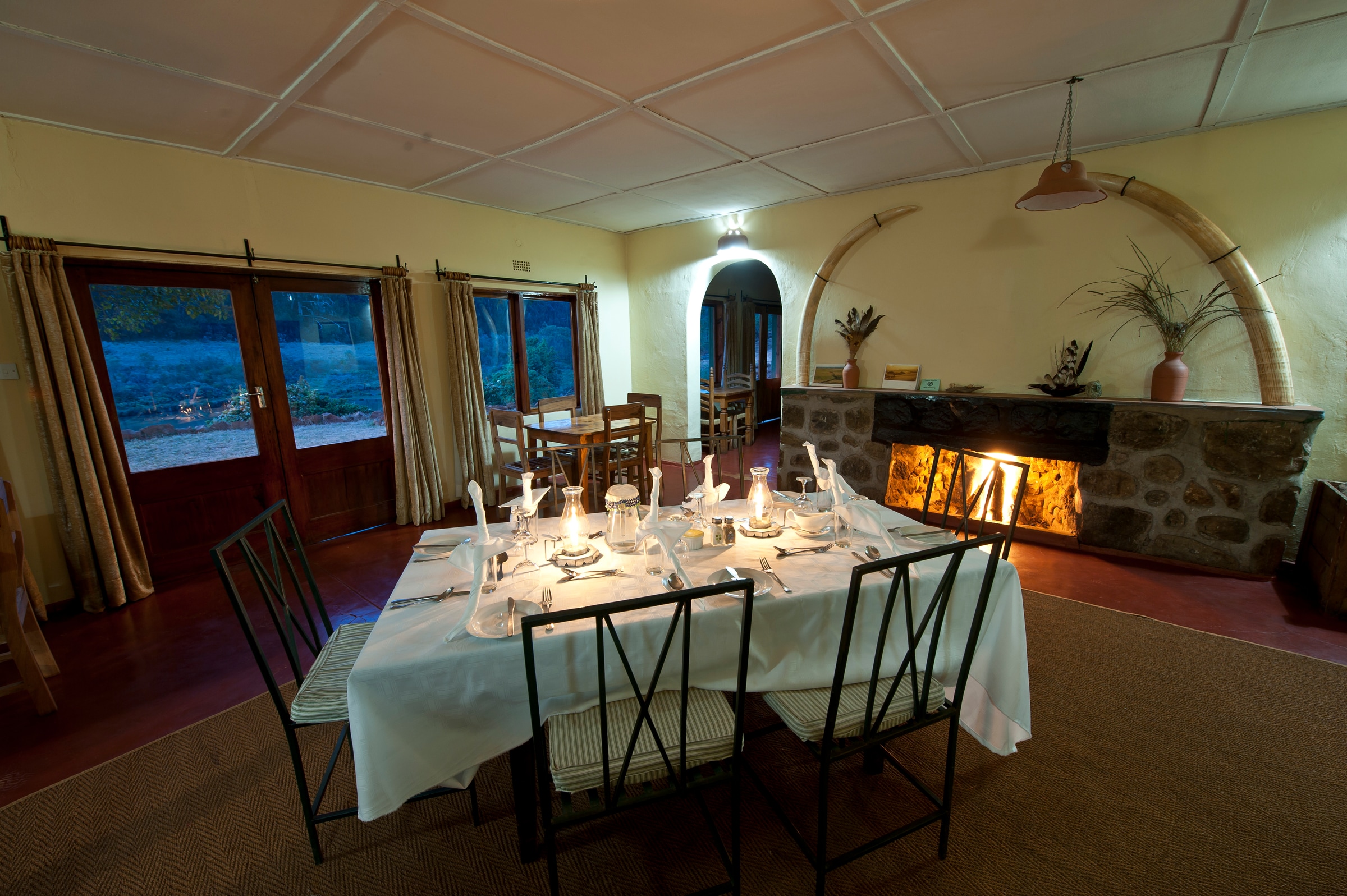 A table set for dinner beside a lit fireplace at Chelinda Camp.